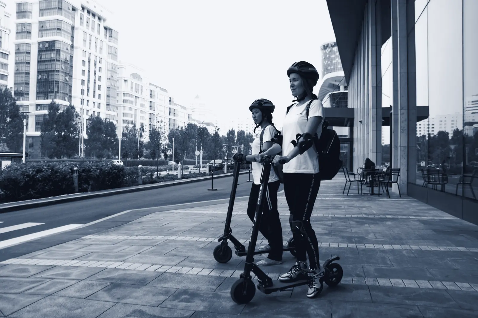 Riders on shared e-scooters on a city sidewalk